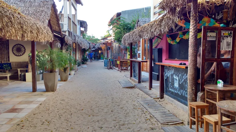 Rua de areia da vila de Jericoacoara com bares e lojas de teto de palha